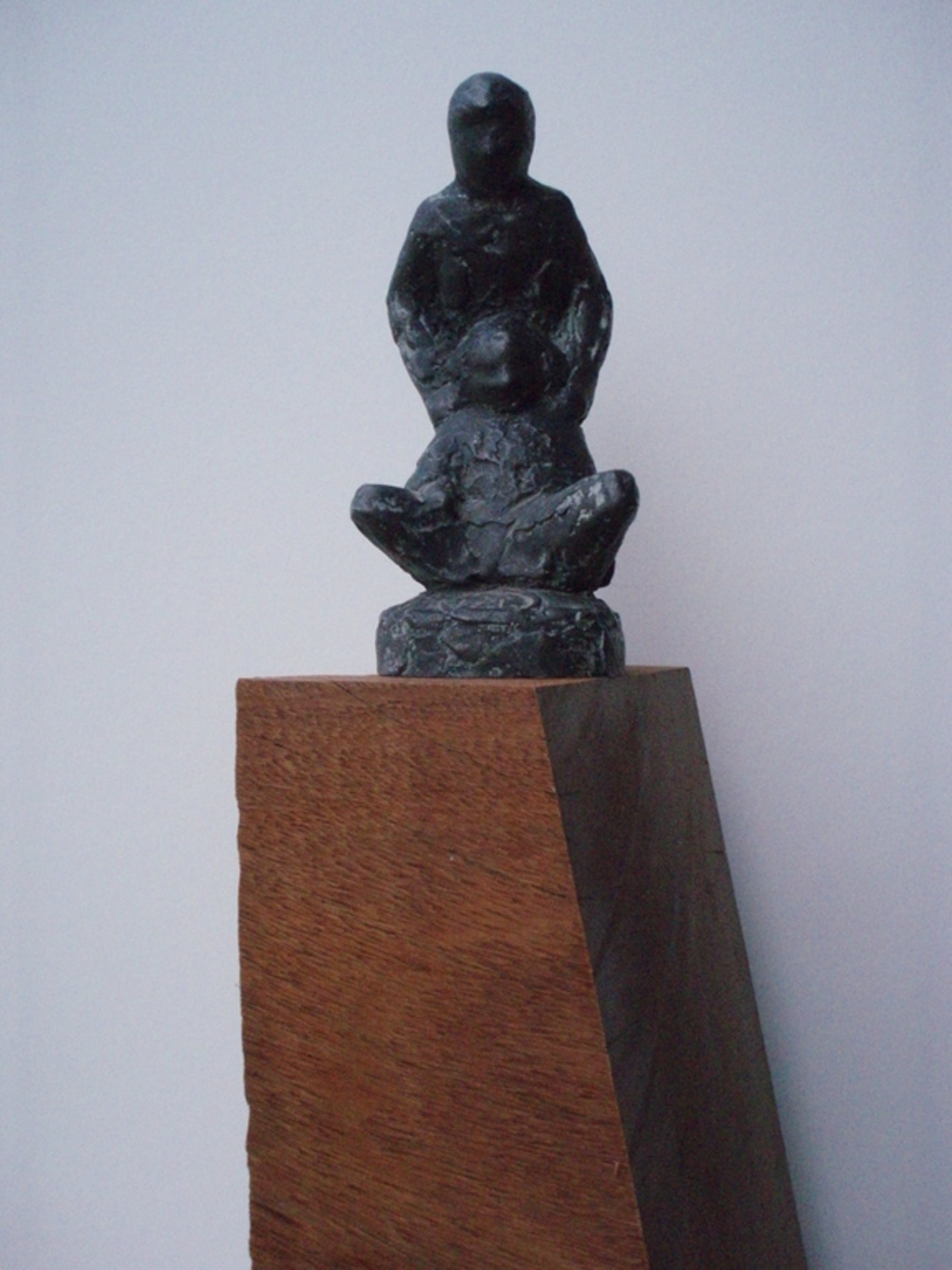 Een modern sculptuur van brons met een een lauriertak op houten sokkel