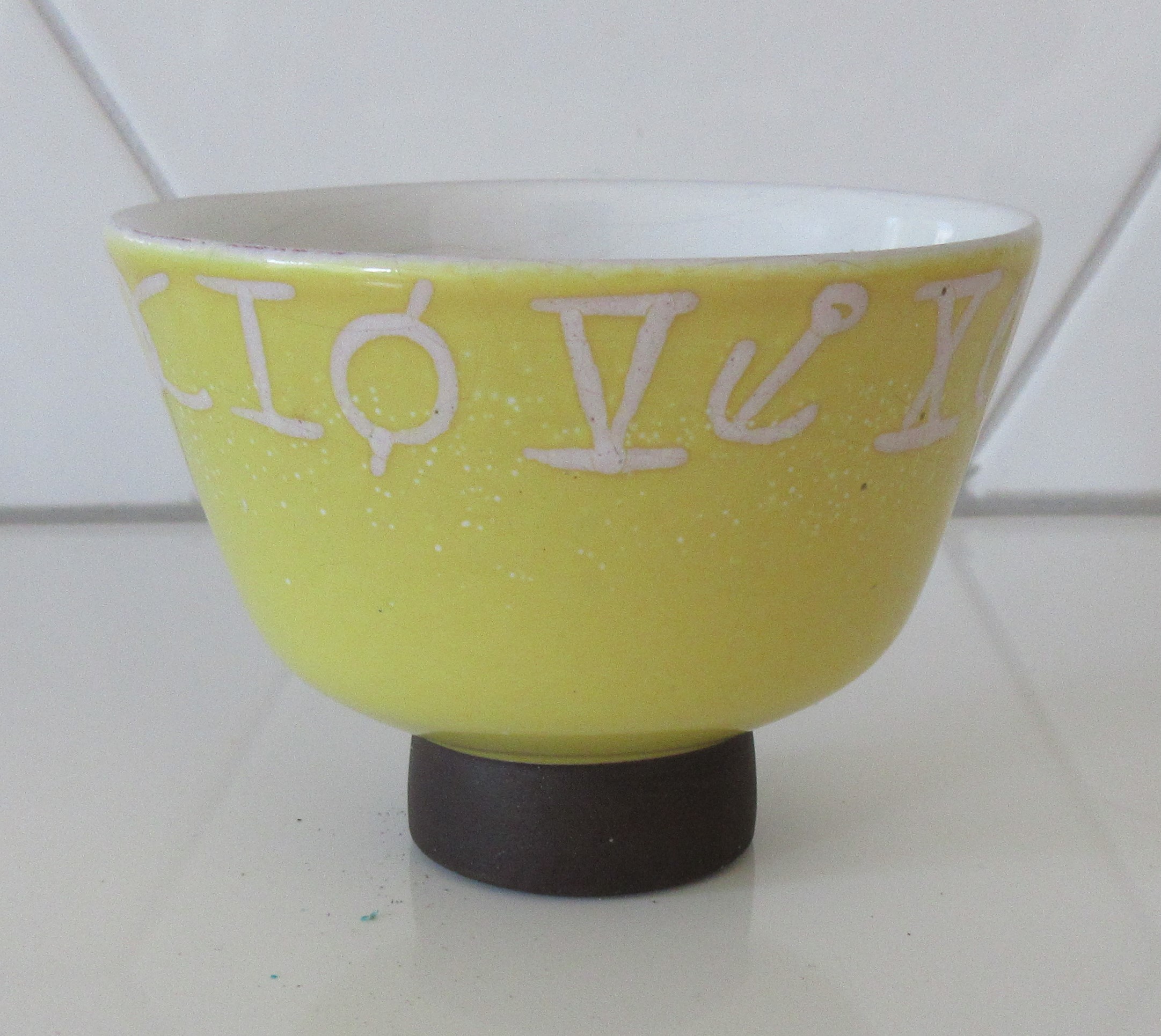 Niet of onleesbaar gesigneerd - Fifties zachtgeel kunstaardewerken schaaltje op bruine ronde voet verkocht voor € 1!