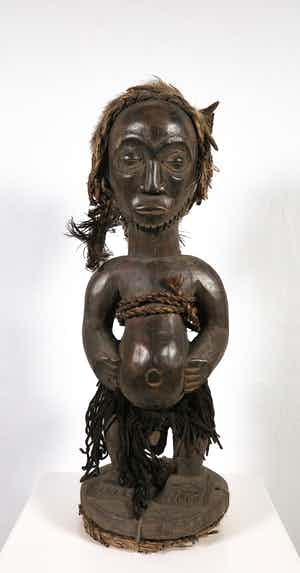 Kusu - Houten beschermbeeld met ringbaard, een kapsel van haar en veren met rugbuidel verkocht voor € 1!