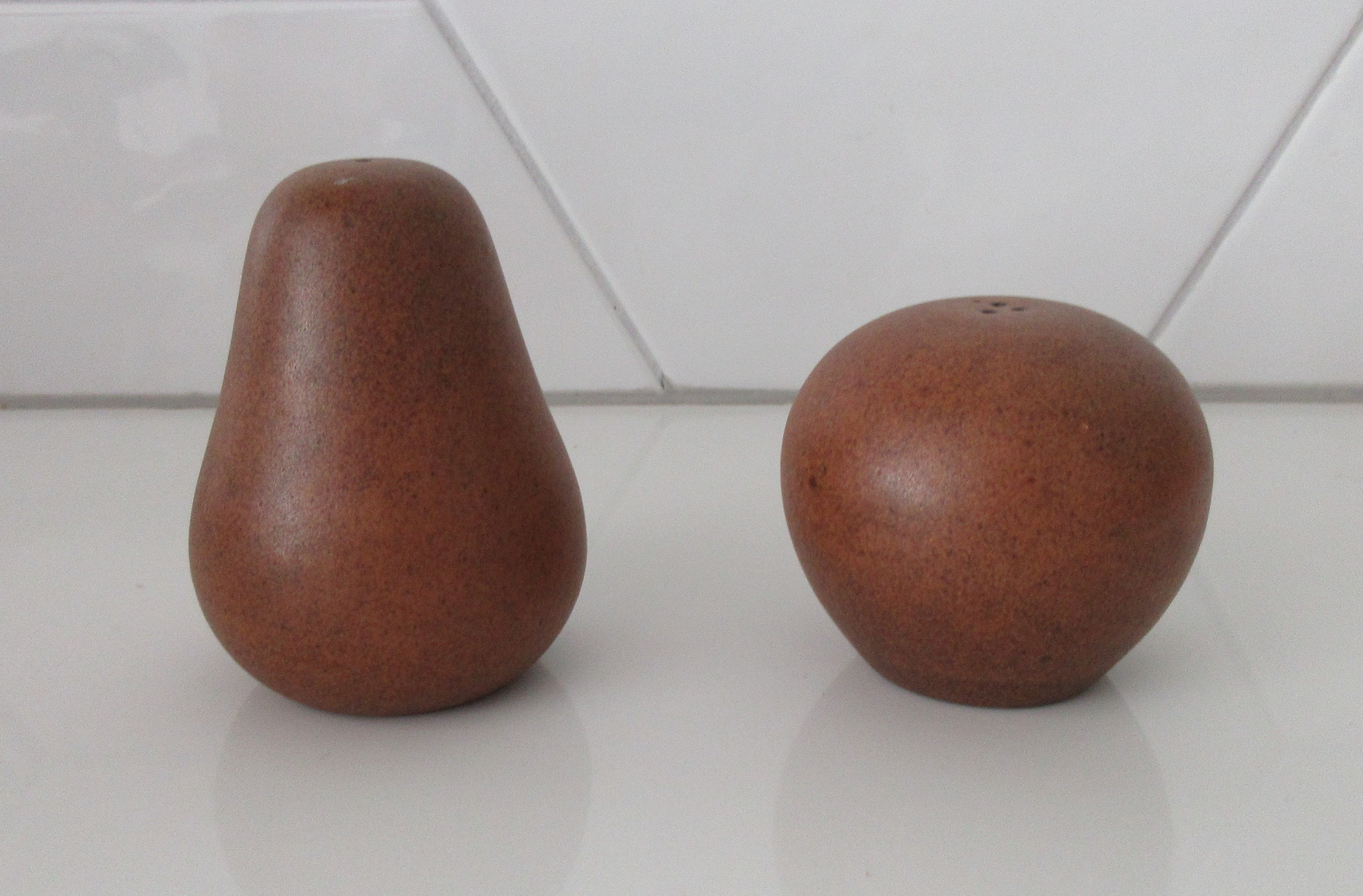 Niet of onleesbaar gesigneerd - Twee gestileerde bruine aardewerken peper- en zoutstrooiers (appel & peer) verkocht voor € 1!
